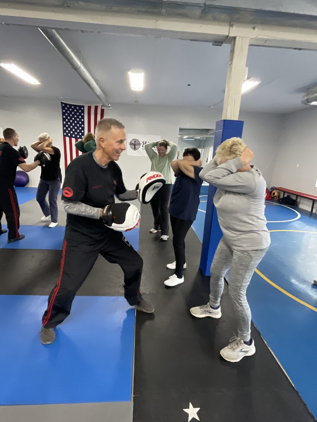 Workshop participants practising strikes on focus pads with an instructor